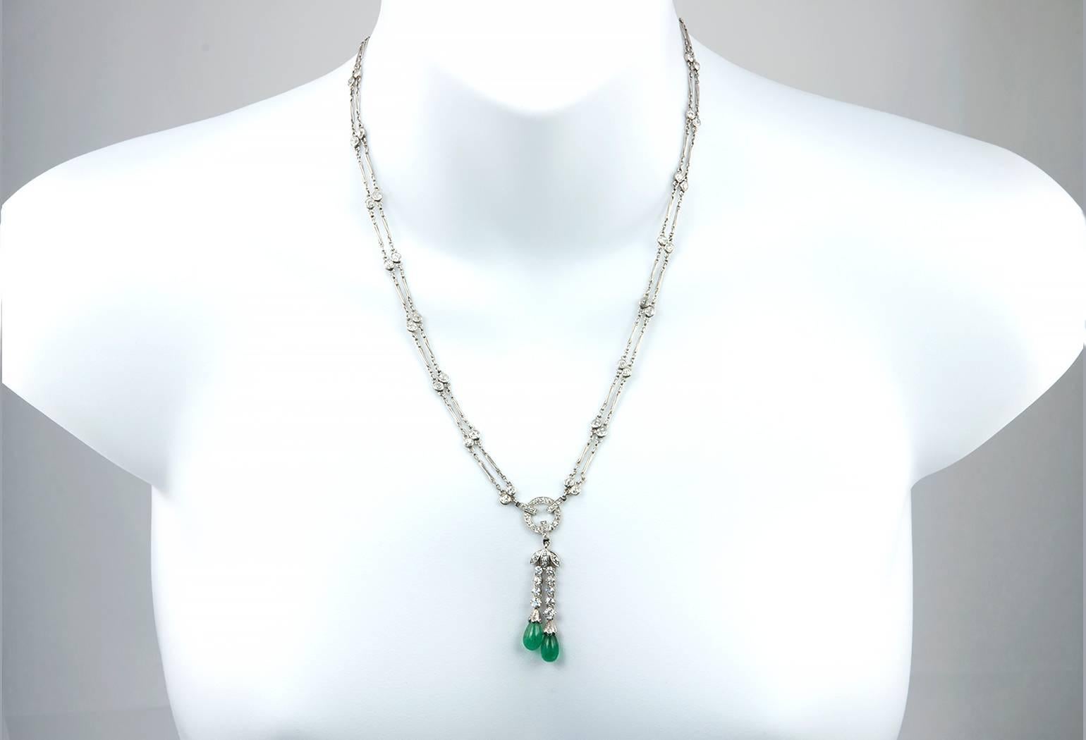 A stunning antique necklace from circa 1920s!  This long necklace features a double platinum link chain that alternates with bezel set diamonds leading down to the center drop of diamonds and 2 polished emeralds.  The 80 Old European Cut diamonds in