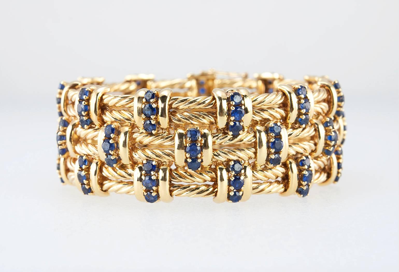A contemporary, wide sapphire and gold braided link bracelet.  The 99 round sapphires are set in 18 karat yellow gold.  Circa 2000.

The bracelet measures approximately 6.75 inches in length, 0.92 inches wide, and 0.20 inches in depth. 