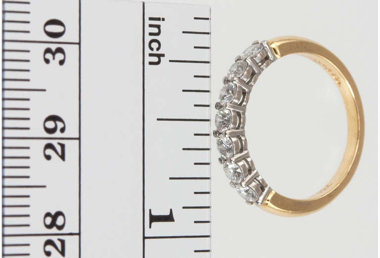 Tiffany & Co. shared-setting band ring in 18 karat gold, with a half circle of 7 round brilliant cut diamonds in platinum, weighing approximately a total of 0.56 carats, circa 1990s, approximately 3mm wide, signed Tiffany & Co. 

Size 5.75 and can