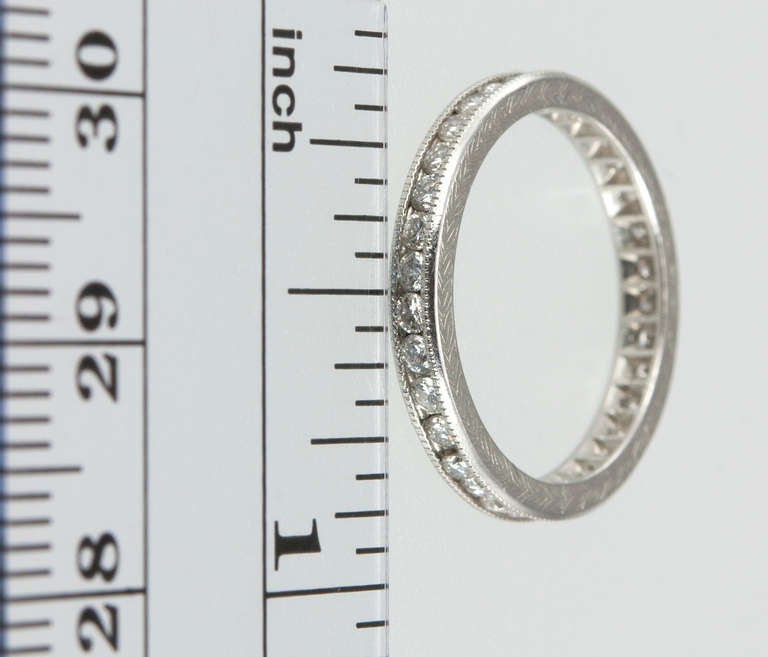 This is a new beautiful platinum diamond eternity band made by our jeweler in the style of a 1920s ring. It features 0.90 karats of bright, round brilliant diamonds accented by a subtle design of engraving that goes all the way around. Size 6.