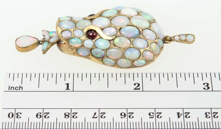 A unique and whimsical Victorian snake head pendant! The snake head is covered in opals with ruby cabochon eyes in 15 karat yellow gold, circa 1870.