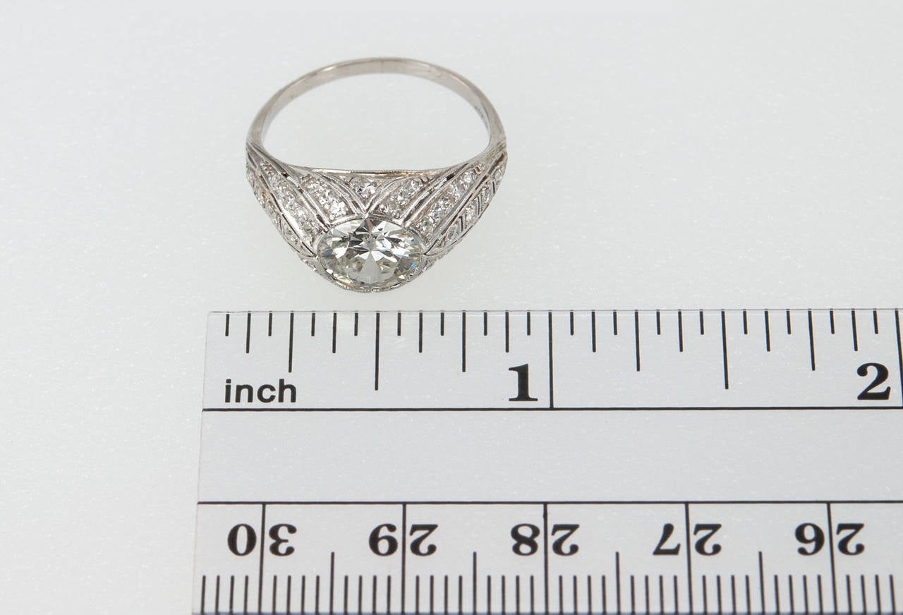 This stunning Art Deco platinum ring features a 1.29 carat transitional round cut I-VS1 (EGL) diamond that is bezel set with 26 round diamonds set throughout (approximately 0.20 carats of total diamond weight). The slight openwork throughout this
