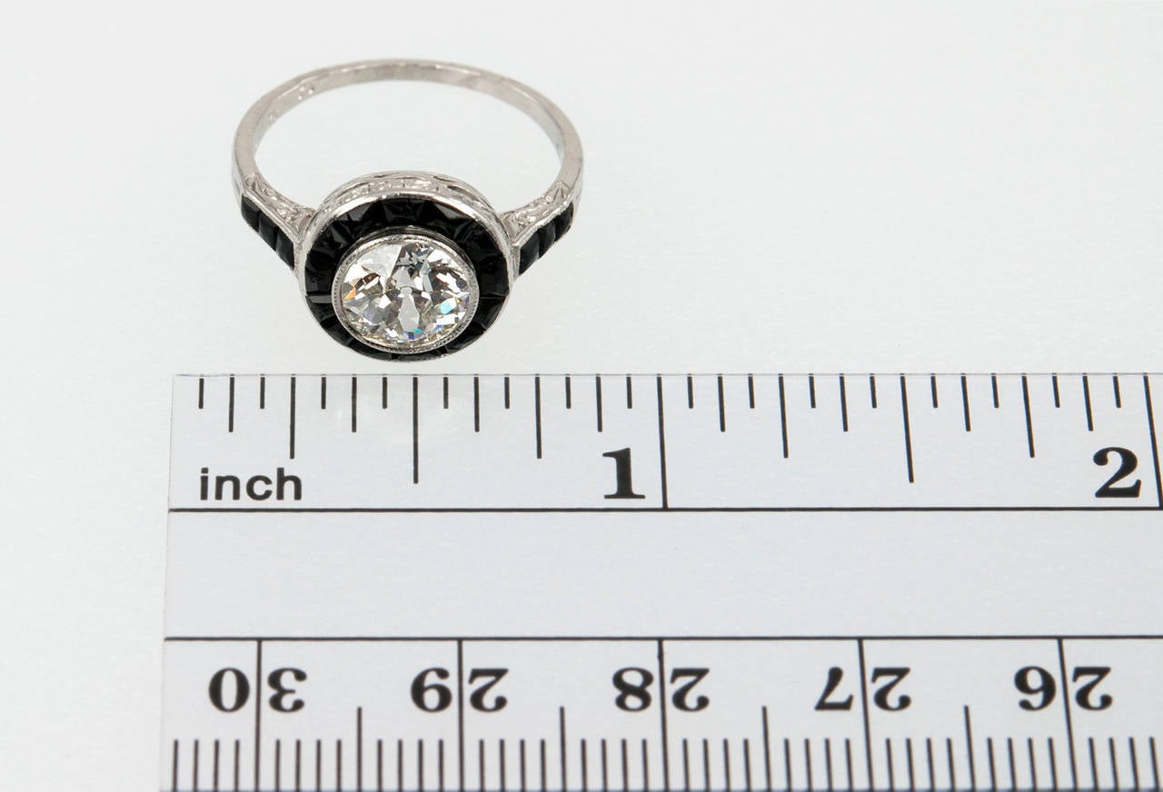 This gorgeous platinum ring features a beautiful bezel set 1.13 carat Old European Cut diamond that is G-H in color and VS2 in clarity with an EGL certificate. The diamond is surrounded by 18 buff cut onyx gemstones that frame the diamond and the