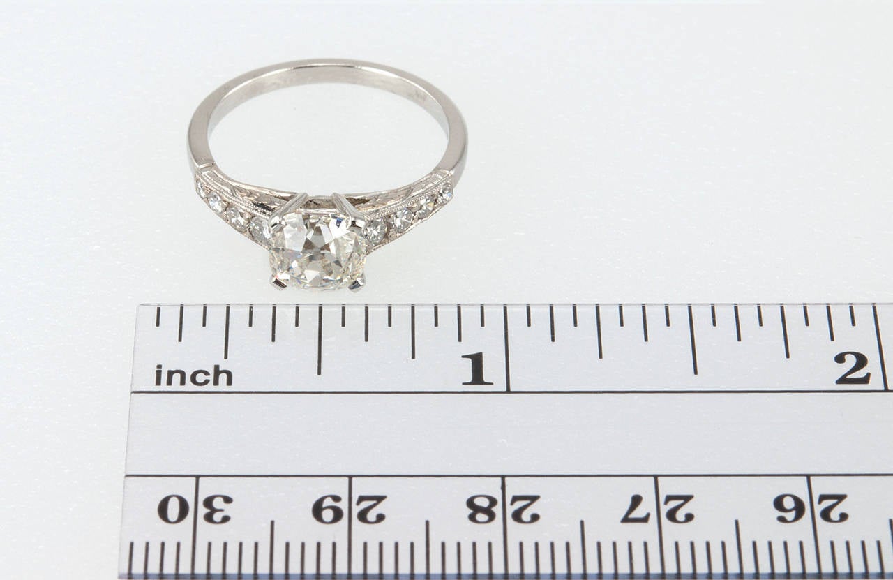 A 1.55 carat cushion cut diamond is featured in this beautiful platinum ring. The center stone is J in color and SI1 in clarity with a certificate from EGL. There is a total of 8 additional diamonds, with 4 round cut brilliant diamonds on each