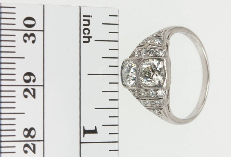 An interesting Art Deco designed diamond ring that features two Old European cut diamonds (approximately 0.50 carats each) and eighteen single cut side diamonds in a geometric design that features open work and millegrain details in platinum, circa