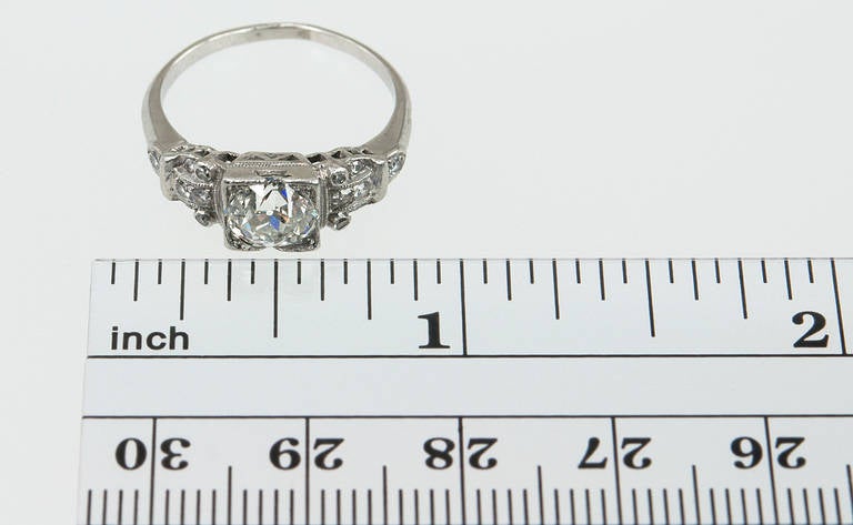 A beautiful Art Deco engagement ring that features a 1.14ct I-VS2 (EGL) Old European cut diamond, which is bead set in a square setting with a total of fourteen small round diamond side stones decorating the symmetrical step mounting, circa 1930s.