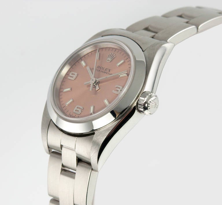 Rolex lady's stainless steel no date Oyster Perpetual wristwatch, Ref. 76080. This watch features a 24mm case with a salmon dial and baton and Roman numerals. A scratch-resistant crystal and locking waterproof crown, circa 2005. Includes box and