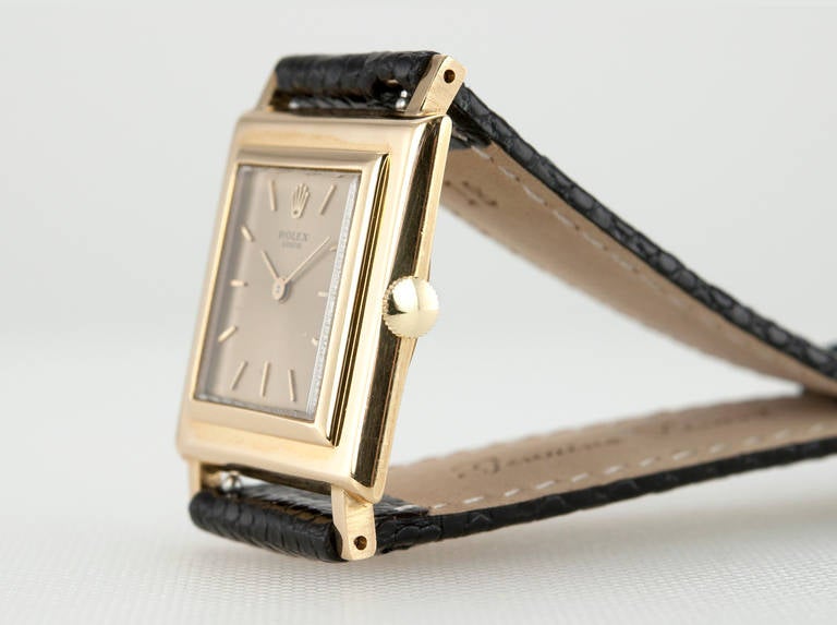 Rolex 18k yellow gold square wristwatch with a screw-back case, original champagne dial, sapphire crystal, manual wind movement in 18 karat yellow gold, circa 1960s. Case measures approximately 26mm width by 26mm height.

This watch includes a one