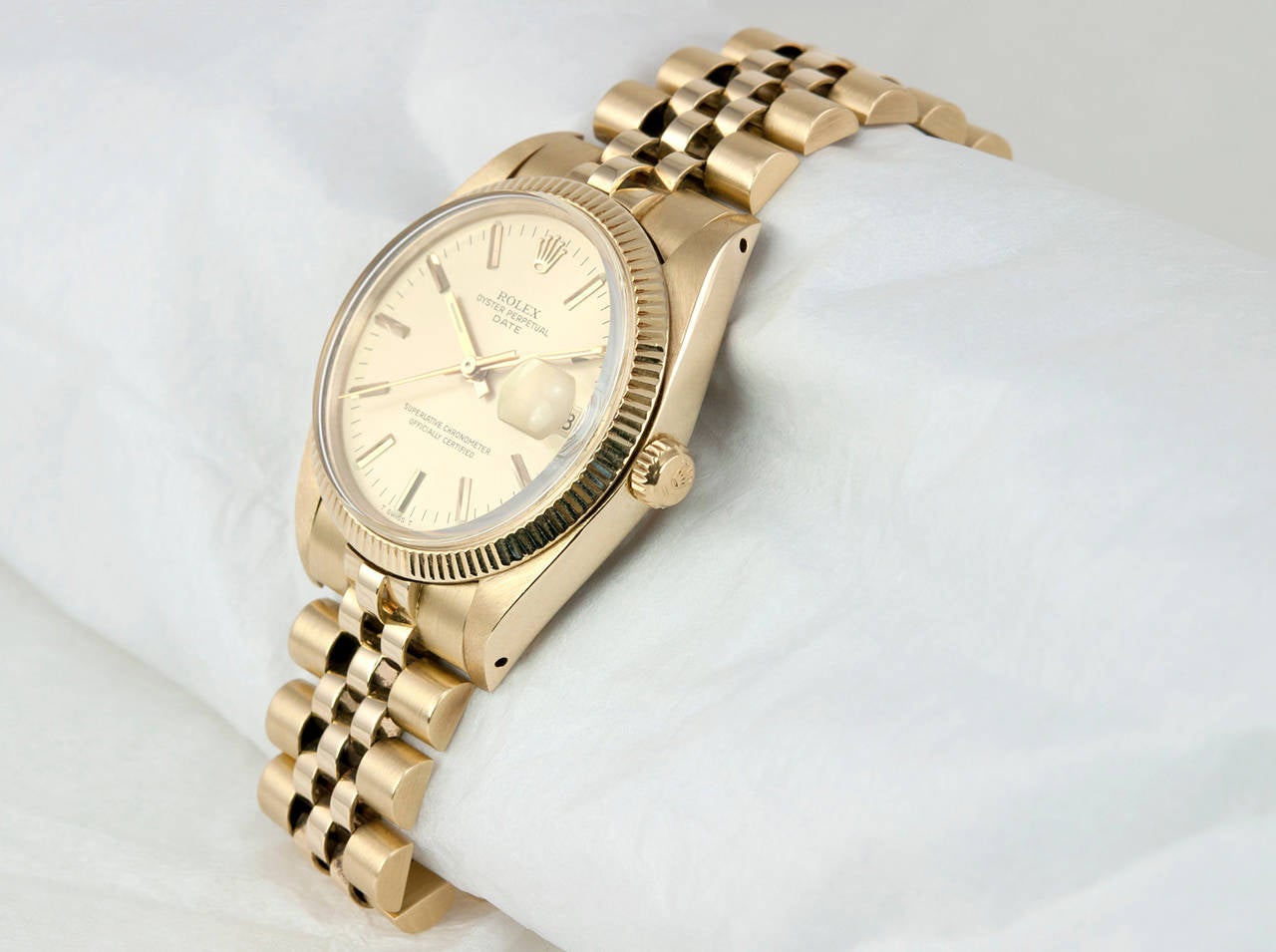 Rolex 14K yellow gold Date wristwatch, Ref. 1503, 1979. Champagne-color dial, plastic crystal, locking waterproof crown, fluted gold bezel, Jubilee bracelet. The case measures approximately 34mm in width.

This watch includes a one year warranty