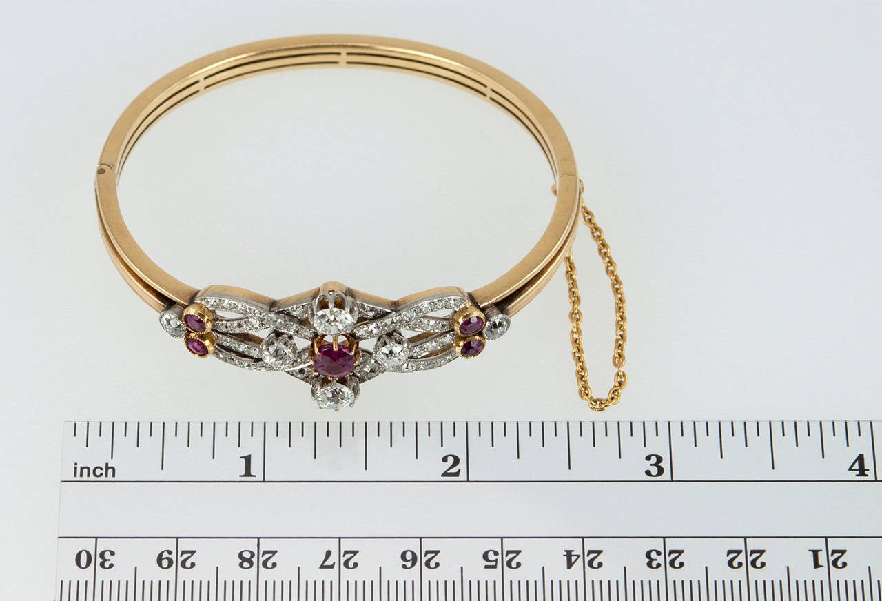 A stunning late Victorian/early Edwardian platinum topped 18 karat yellow gold bangle bracelet. The center ruby is approximately 1 carat and believed to be from the Burma region. The bracelet also features two diamonds above and below the ruby that