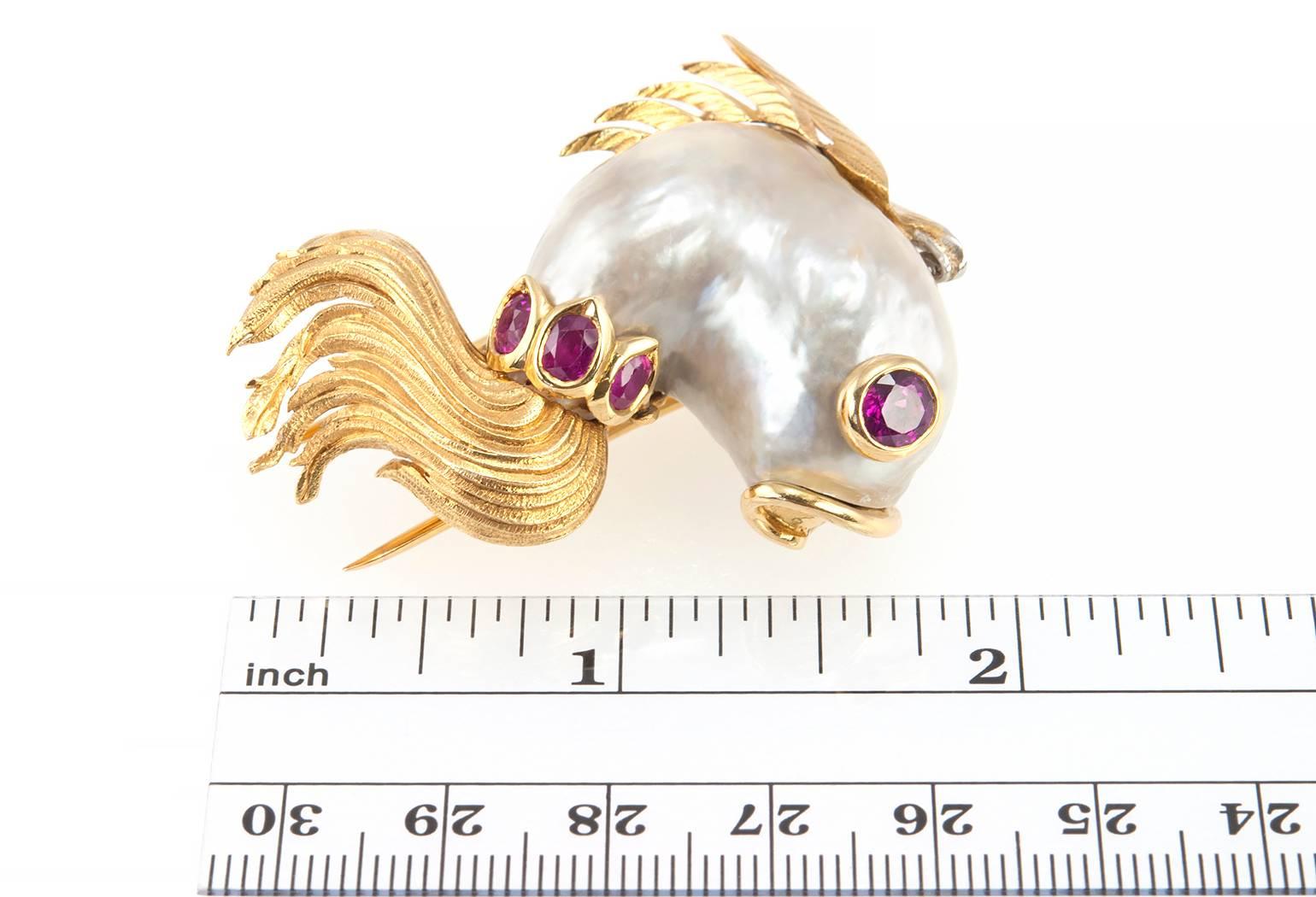 A fabulous and whimsical Cartier fish brooch featuring a freshwater pearl with 4 natural rubies and 16 single cut diamonds along the top fin in 18 karat yellow gold. Circa 1960s. The brooch measures approximately 1.97