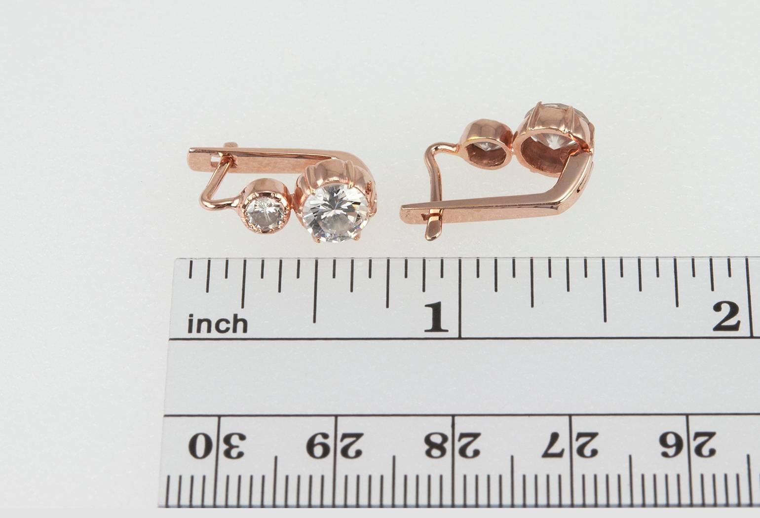 A pair of diamond earrings you won't want to take off! These 14 karat rose gold earrings feature two round brilliant cut diamonds per earring with the smaller of the diamonds (approximately 0.15 carats each) bezel set above the larger diamond