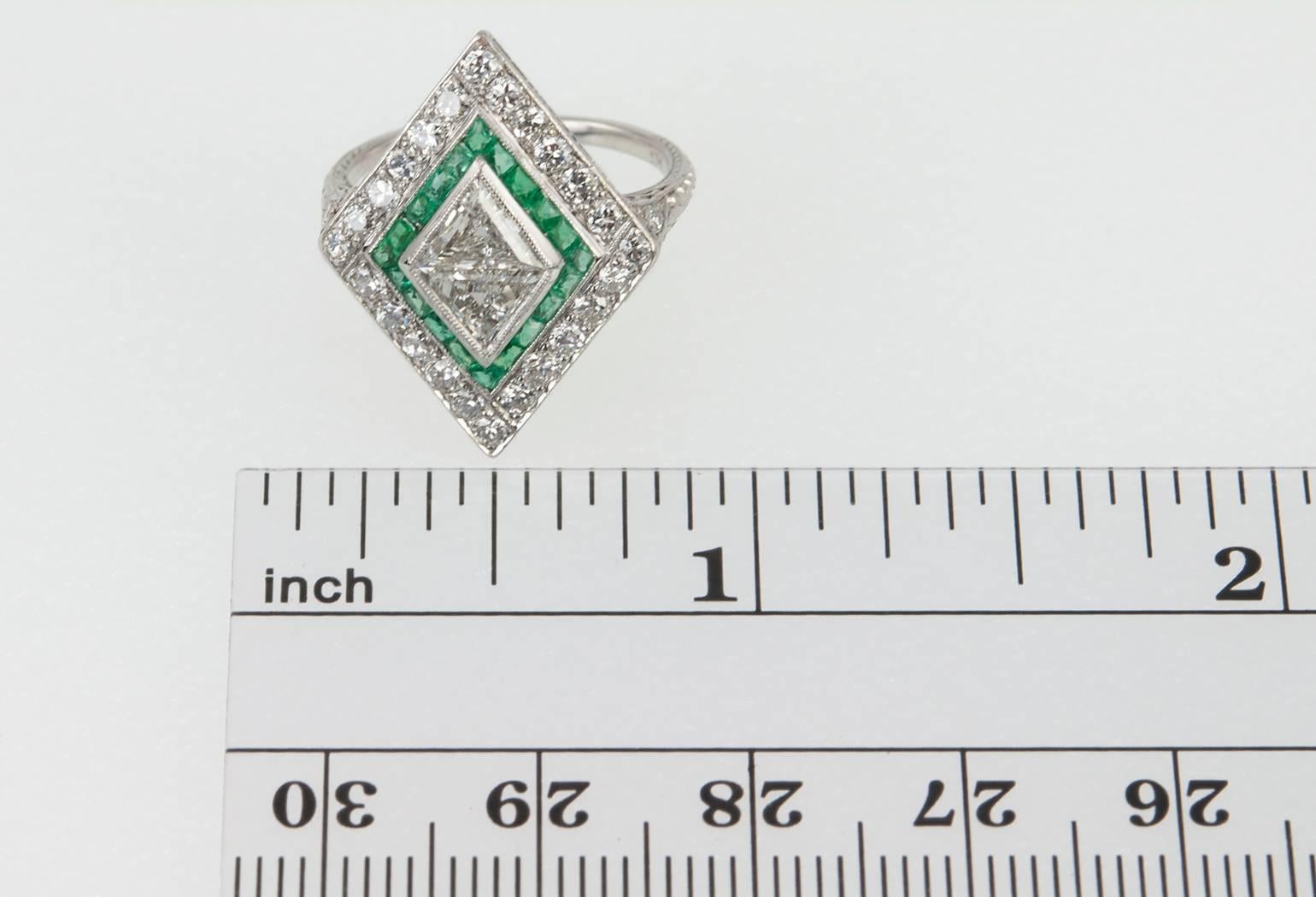 A gorgeous diamond and emerald kite-shaped platinum ring! This ring features 2 trillion cut diamonds, one diamond is 0.34 carats G in color and SI1 in clarity and the other is 0.40 carats G in color and VS2 in clarity (per EGL certificates). The