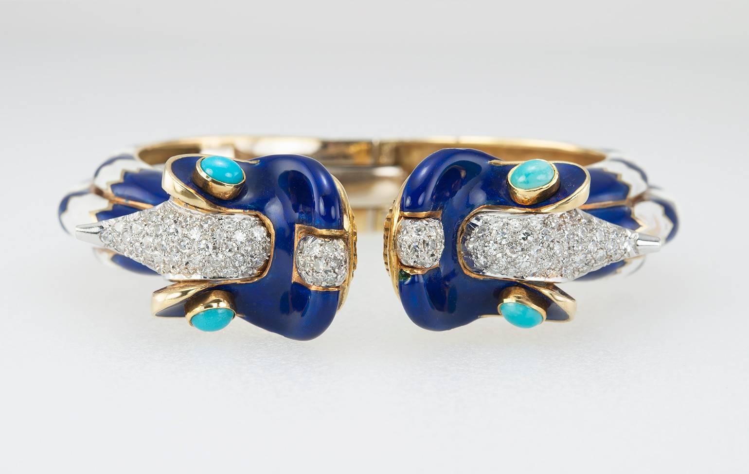 Double dragon hinged cuff bracelet in 18 karat yellow gold from circa 1960s. This very cool piece features blue and white enamel, turquoise cabochon eyes and approximately 2 carats in total diamond weight that make the dragon heads really pop! 