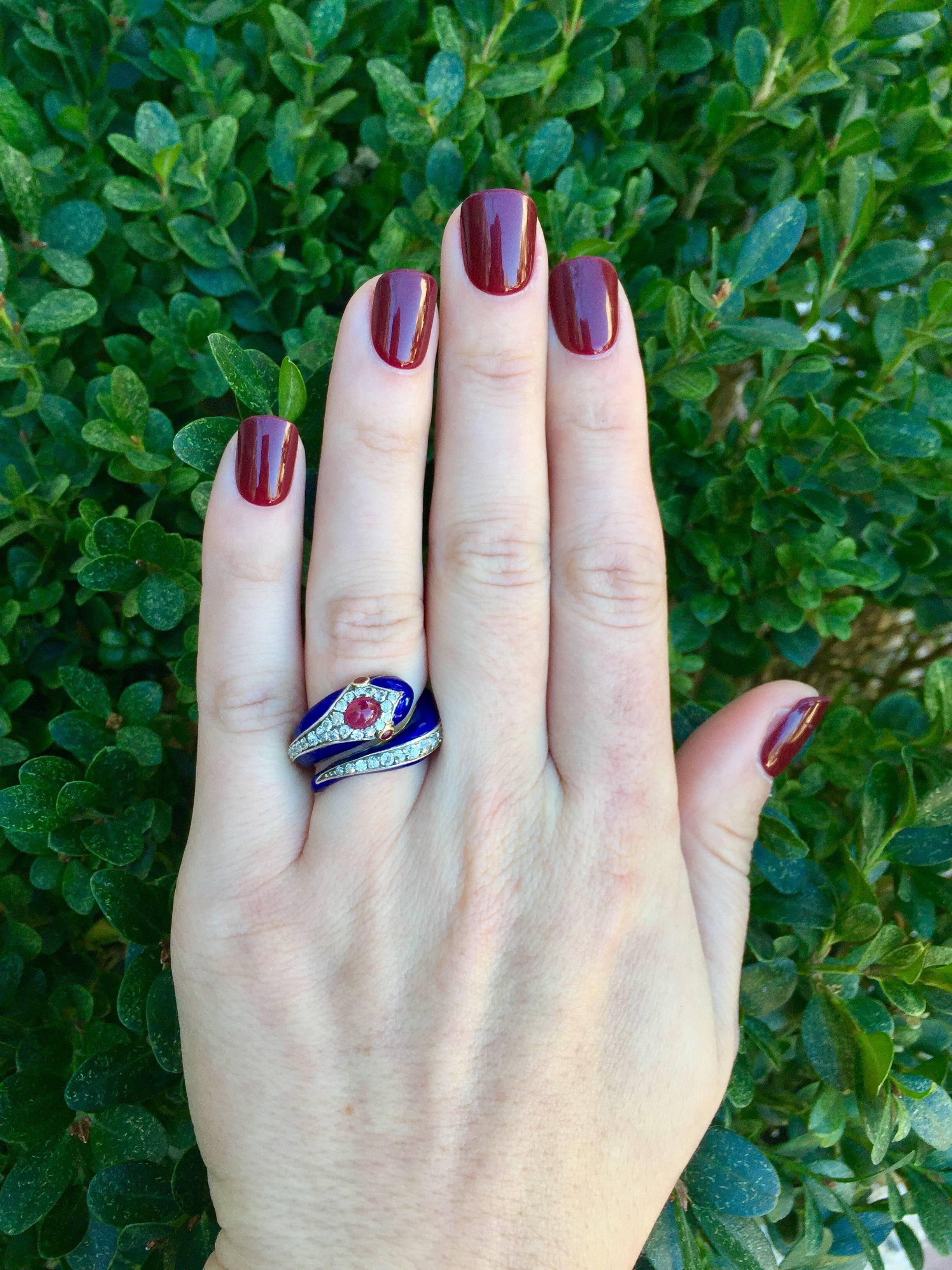 This vintage 18 karat yellow gold and platinum snake ring has beautiful dark blue enamel on its body.  37 old cut diamonds are set around the curved body, totaling approximately 1 carat in diamond weight.  A ruby cabochon is set on the snake head