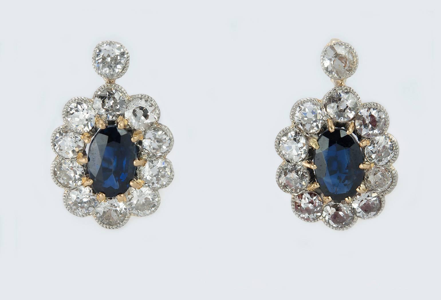 Victorian platinum topped 18 karat yellow gold sapphire and diamond drop earrings.  These stunning sapphire and diamond clusters feature 2 center sapphires that are approximately 0.75 carats each along with an approximate total diamond weight of 3