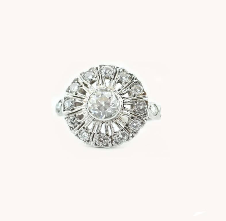 A beautiful diamond and platinum antique Edwardian cluster ring, circa 1910.  This gorgeous ring features a bezel set Old European Cut diamond ring at the center.  Per the EGL certificate, the center diamond is 0.65 carats, I in color and VS1 in