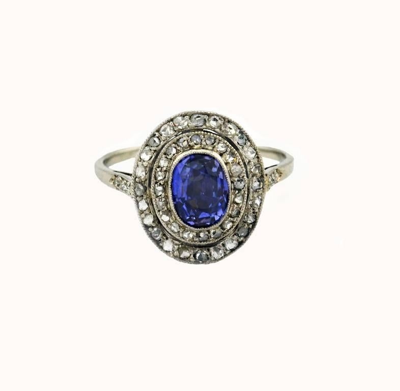A gorgeous Edwardian sapphire and diamond platinum ring, circa 1910.  This cluster ring features a center oval shaped sapphire, approximately 0.75 carats, with a beautiful violetish-blue color.  The sapphire is surrounded by 2 rows of rose cut