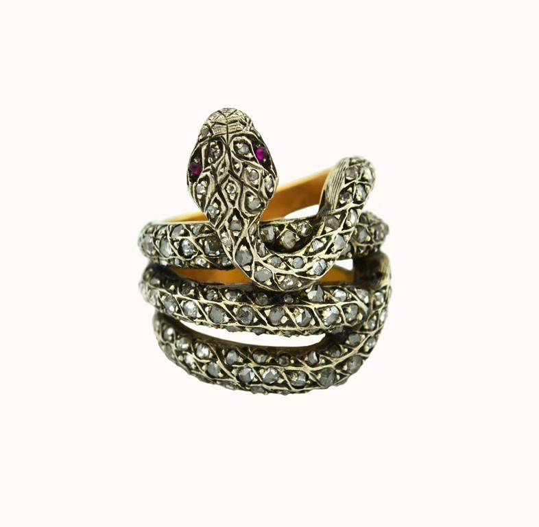A very cool contemporary snake ring crafted in the Victorian style.  This silver topped 18 karat yellow gold ring features a coiled snake covered in rose cut diamonds and 2 ruby cabochons for its eyes. Circa 2000s.

Currently a US size 8 and not