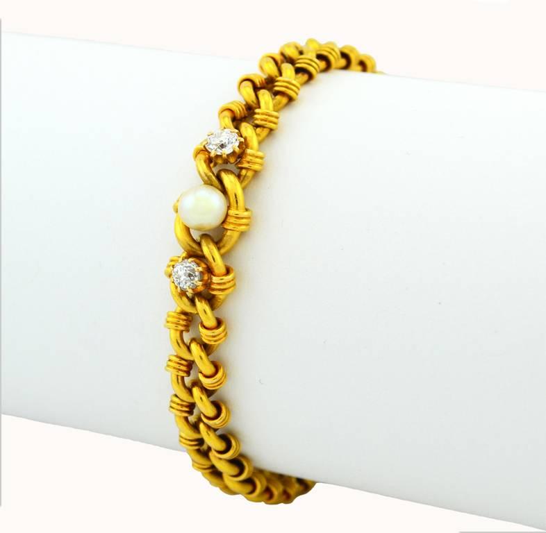 A Victorian gold link bracelet in 18 karat yellow gold.  This lovely antique bracelet features a pearl center, approximately 5.5 mm, and two Old Mine Cut diamonds, each approximately 0.25 carats for a total diamond weight of 0.50 carats.  Additional