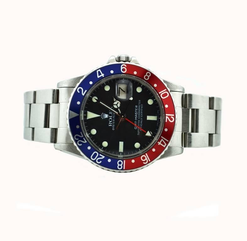 Rolex GMT Master stainless steel wristwatch, reference 16750. This classic Rolex features a black dial, a blue and red aluminum bezel (Pepsi bezel), plastic crystal, locking waterproof crown, and a steel Oyster bracelet, and a Rolex service dial,