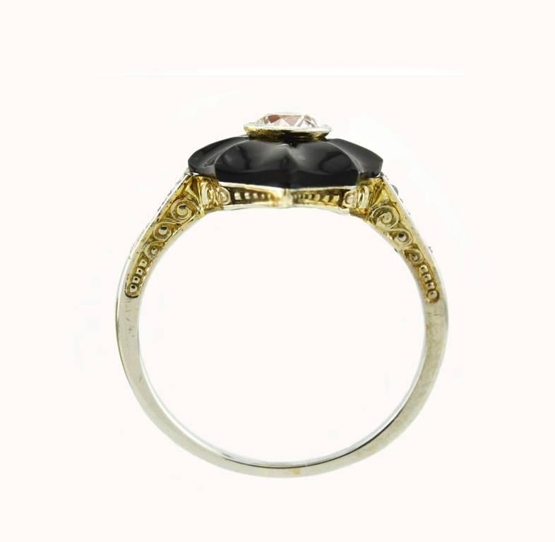 An Art Deco cocktail ring in 18 karat white gold from circa 1920.  This striking ring features carved onyx in navette shape with a bezel set Old European Cut diamond in the center.  The bright diamond is approximately 0.45 carats, I-J in color and