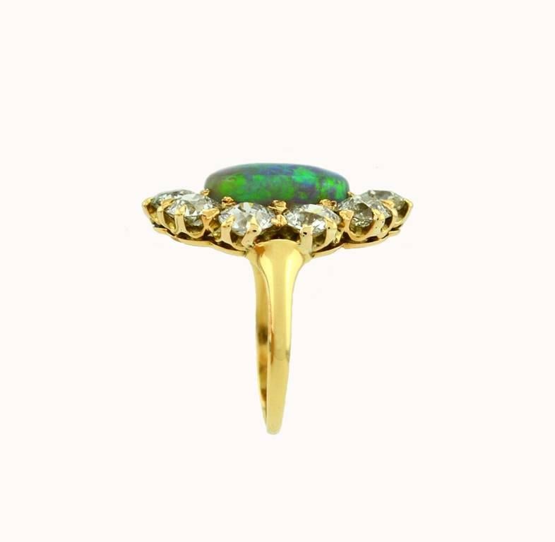 A Victorian opal and diamond cluster ring in 14 karat yellow gold from circa 1890s-1900.  This gorgeous ring features an opal cabochon center with amazing play of color.  The opal is surrounded by 10 Old European Cut diamonds, approximately 2.5