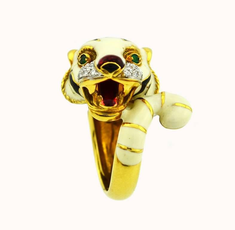 A very cool tiger ring in 18 karat yellow gold from circa 2000s.  This awesome ring features a tiger articulated in cream, black, and red enamel and further accented with 18 round diamonds on its face and 2 emeralds for its eyes.  Italian hallmark