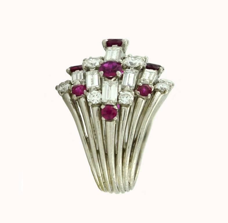 Van Cleef & Arpels ruby and diamond cocktail ring in platinum, circa 1960.   This awesome ring features 11 round rubies, 16 diamond baguettes and 12 round diamonds. The total diamond weight is approximately 3.40 carats. 

Currently a US size 5.25