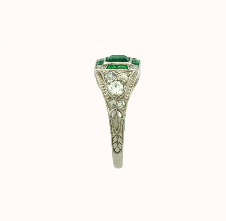 An Art Deco emerald and diamond platinum ring from circa 1920.  

This beautiful ring features a 0.45 carat bright emerald center along with 6 calibre cut emeralds, which total approximately 0.27 carats. And further decorating the setting are 14 Old