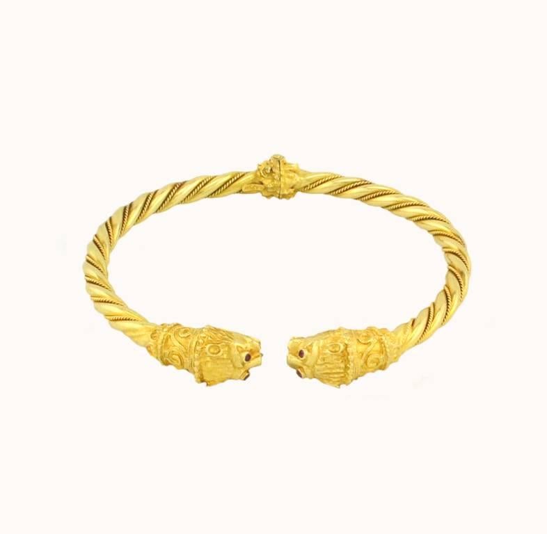 A double lion head bracelet in 18 karat yellow gold with a twist pattern.  The bracelet is constructed with a hinge that opens to allow easy wear on and off! Fantastic details including four ruby eyes on the lion's head. Circa 1980.

This bracelet