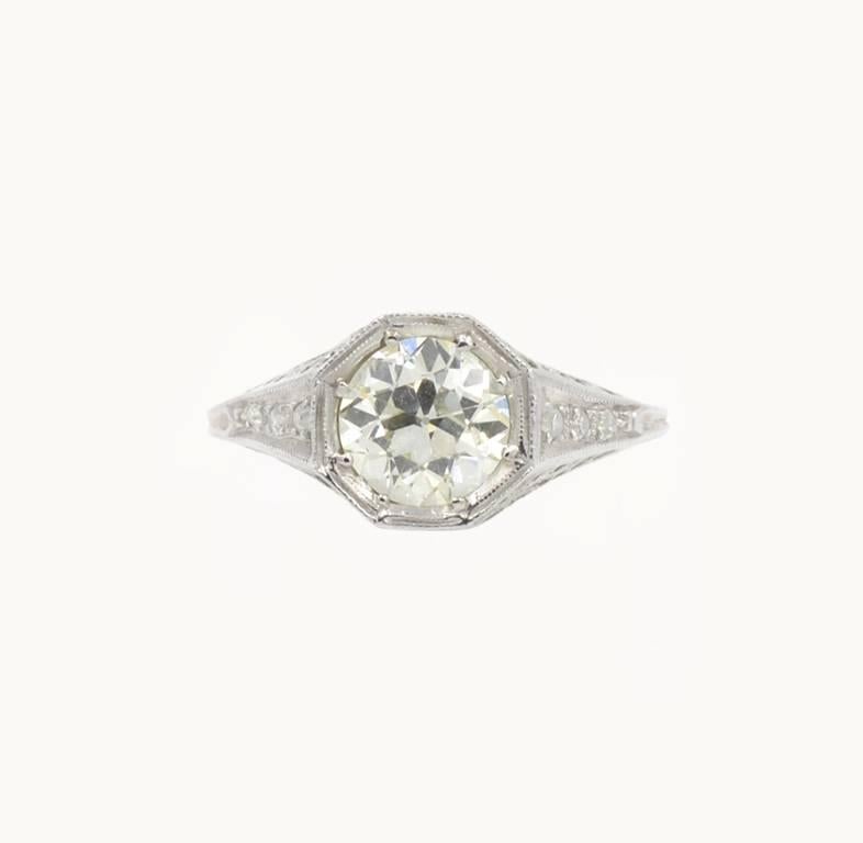An antique Edwardian diamond engagement ring in a platinum filigree setting with three single cut round diamonds on each shoulder of the ring. The center 1.25 Old European Cut diamond is K in color and SI1 in clarity (per EGL certificate) and set in