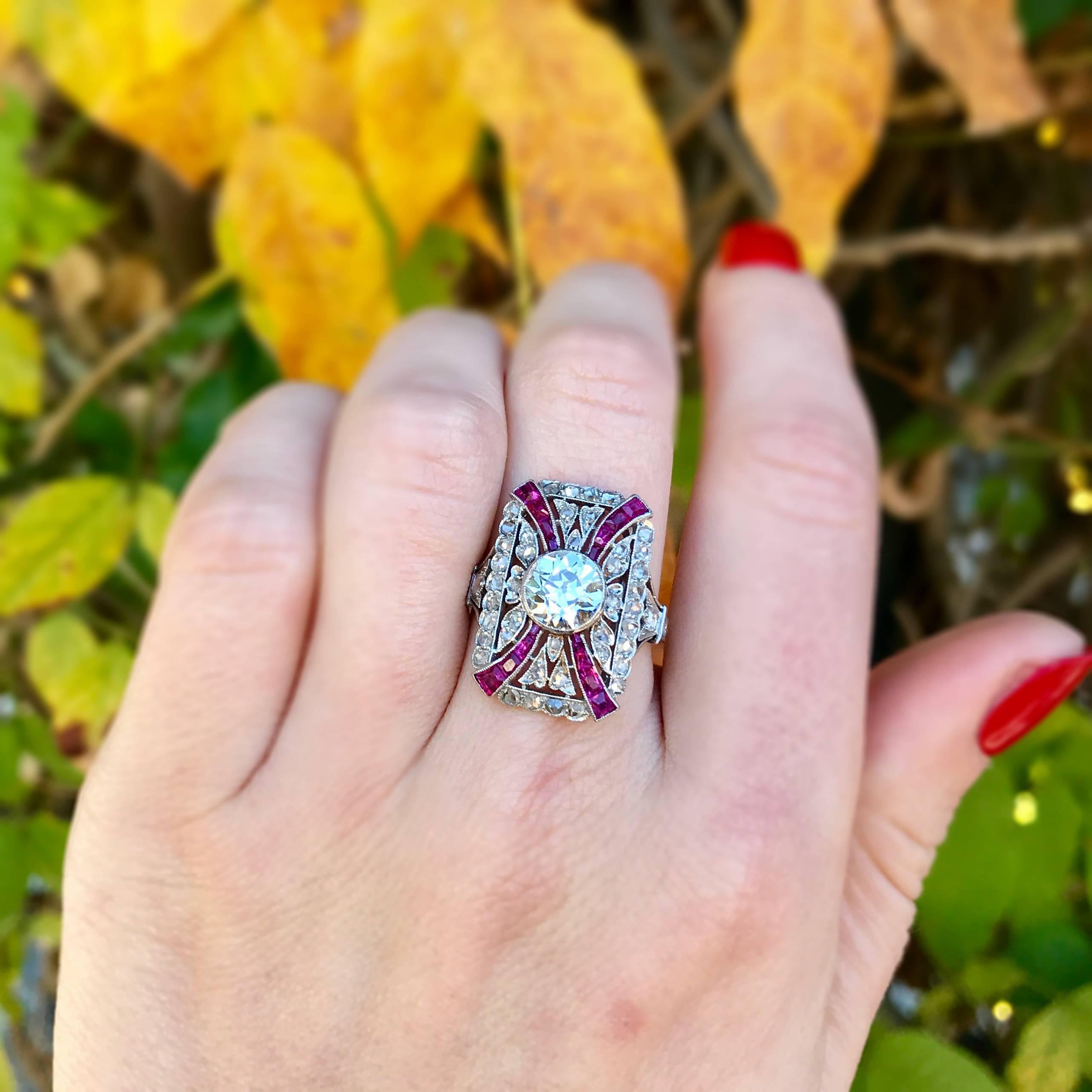 A stunning antique Edwardian diamond and ruby ring from circa 1910. This large platinum ring is studded with rose cut diamonds and four channels of rubies leading to a bezel set Old European Cut center diamond approximately 1.75 carats that is J in