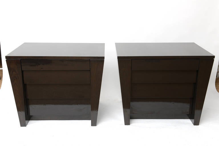 Pair of ebonized oak chests that taper on the sides as well as in the front. They each feature four drawers on gliders and they recess in the fronts as they go down complimenting the already tapered sides. The quality and finish are impeccable with