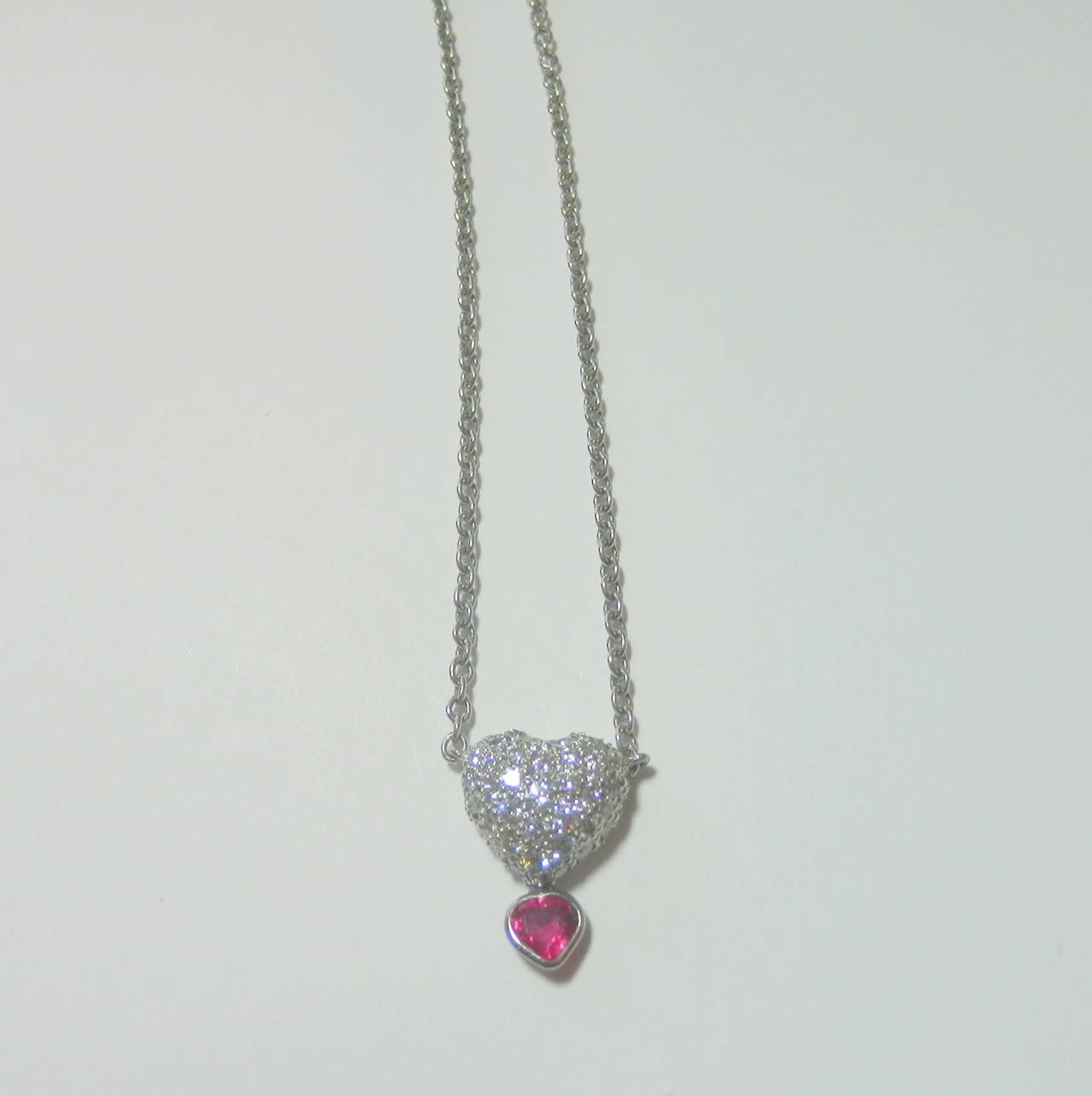 Platinum, diamond and ruby pendant.  The small heart shaped ruby has a sweet Burma color and is approximately .10 cts.  The diamonds (.25 cts.) are all H/I, VS1 and full brilliant cuts.  The hearts are approx. 1/2 inches in length and the total
