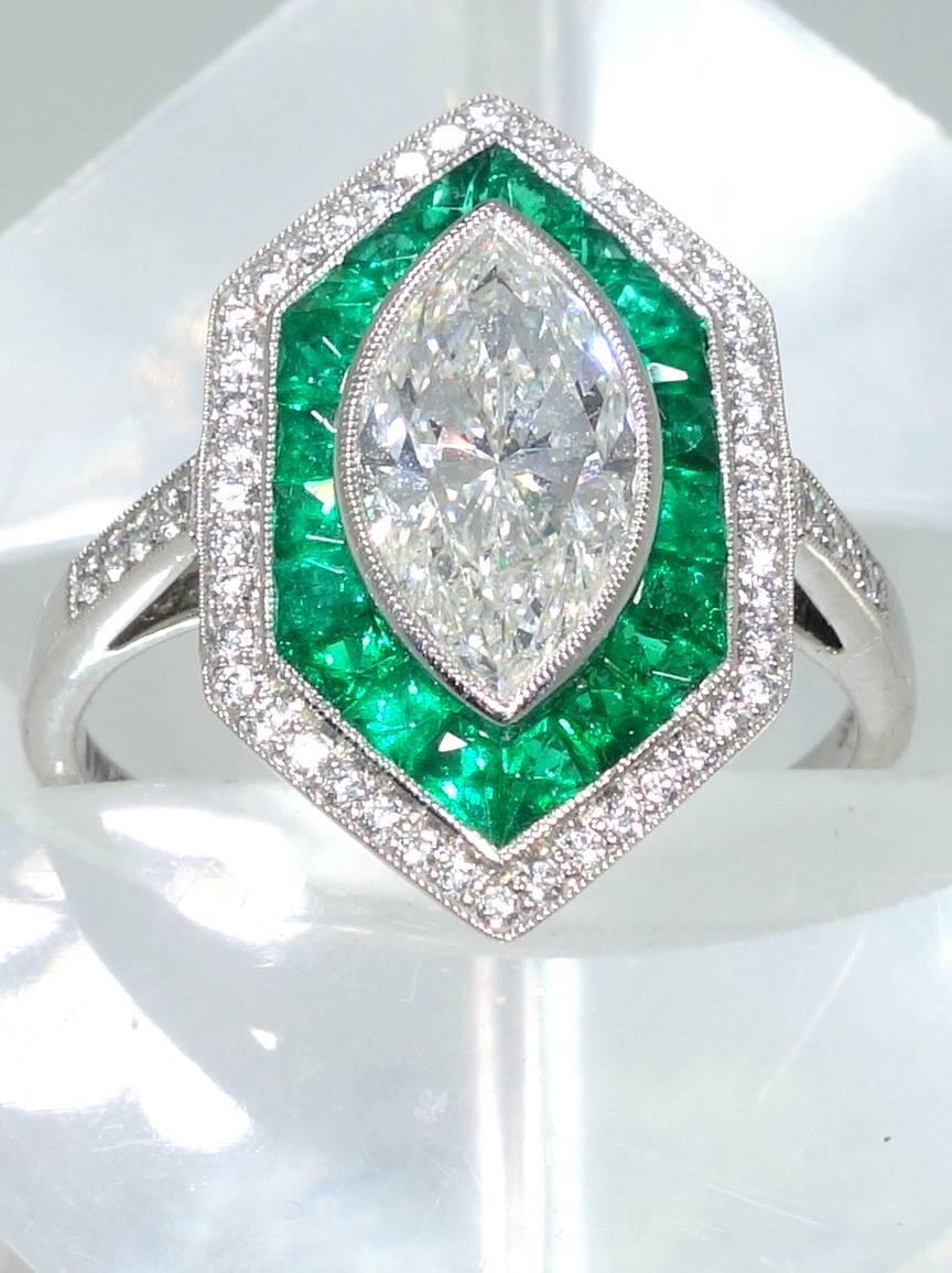 The center diamond is a 1.36 ct. fine marquis cut diamond accompanied by a G.I.A. certificate stating this stone is a G (near colorless) and VVS1 (very very slightly included to a first degree).  It is surrounded by fine natural fancy cut Emeralds