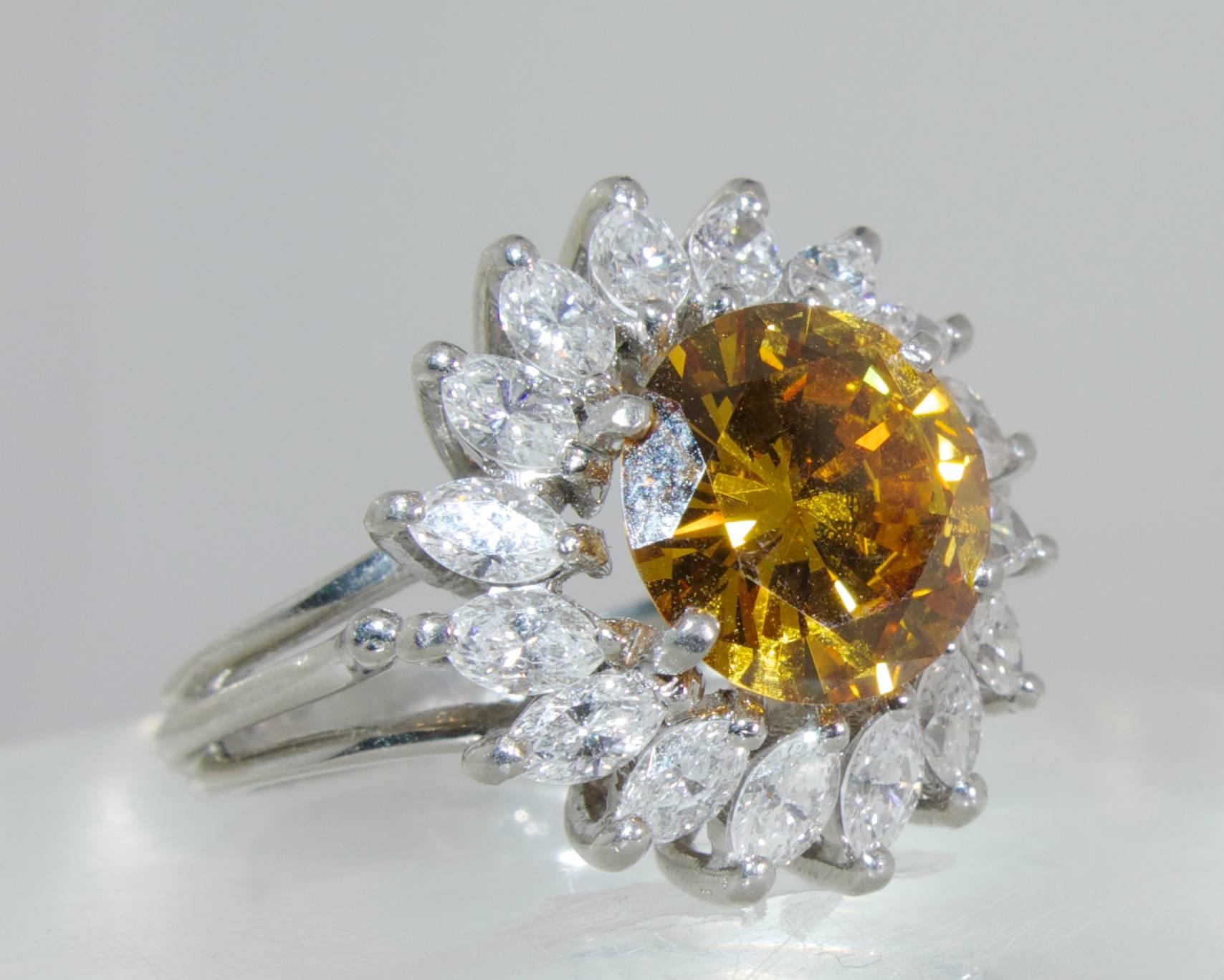 The center brilliant cut diamond displays a bright cognac color, it weighs 2.68 cts.  This diamond has been examined by the G.I.A. (Report No. 2430550), and is treated color.  The white marquis cut diamonds surrounding this stone weigh approximately
