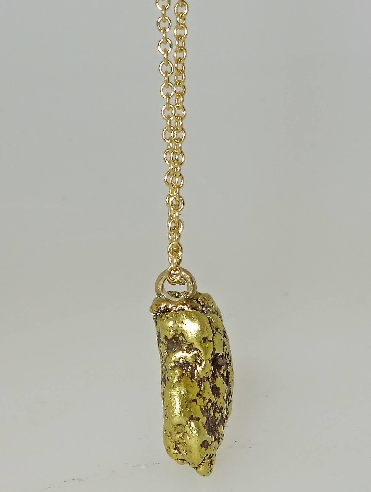 Suspended from a modern 18K chain, this old Alaskan gold nugget weighs 11.8 grams with the chain.  The nugget measures 16.6 mm (length), 14.9 mm (width), and a thickness of 7.5 mm.  Note: 25.4 mm to the inch.  The gold content is 80% (+ or - 5%).