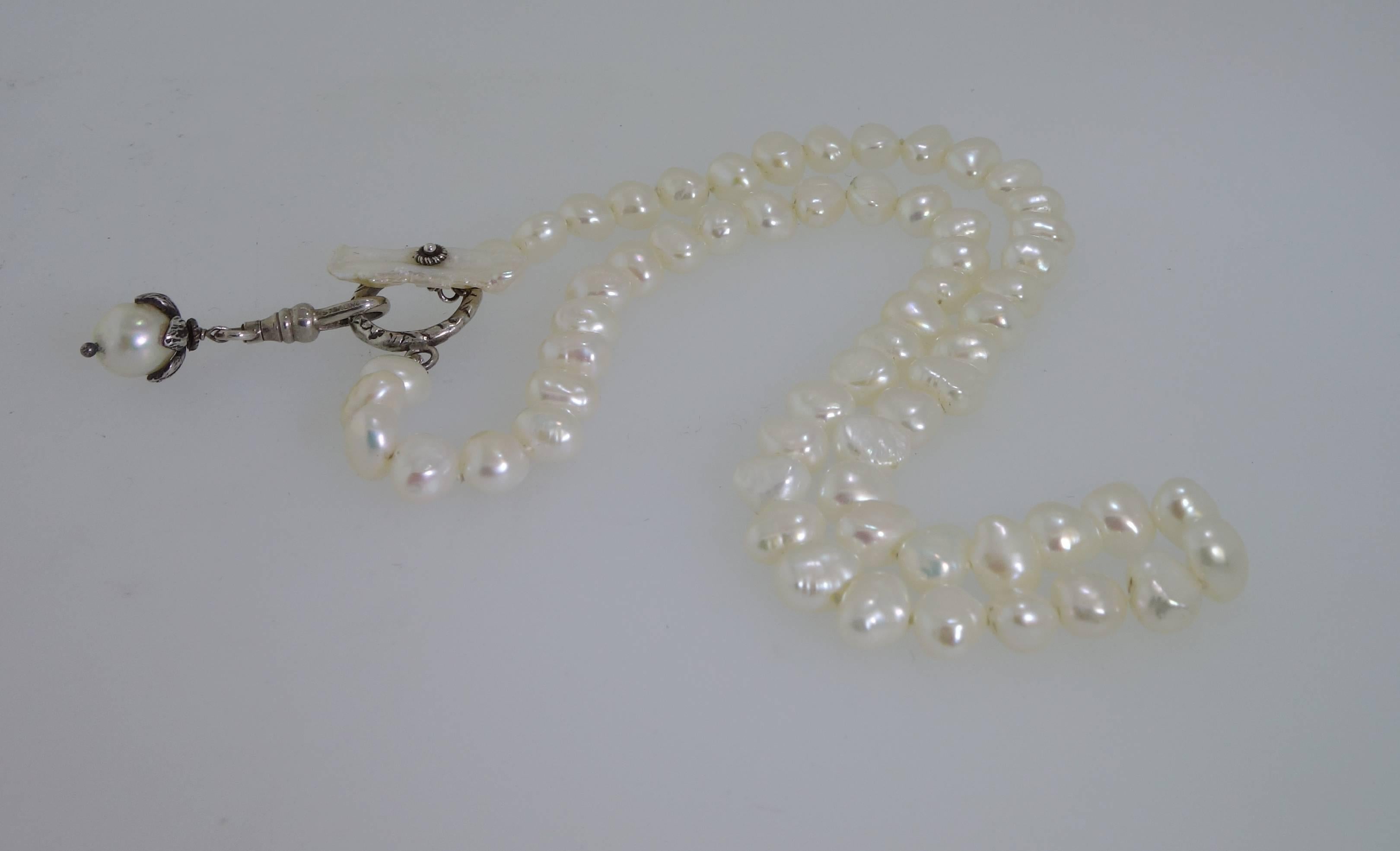 Finished with a sterling silver "toggle" type clasp, this strand is 17 inches long and is a pretty statement for the neck.  The freshwater pearls are white with a fine degree of  iridescence. 