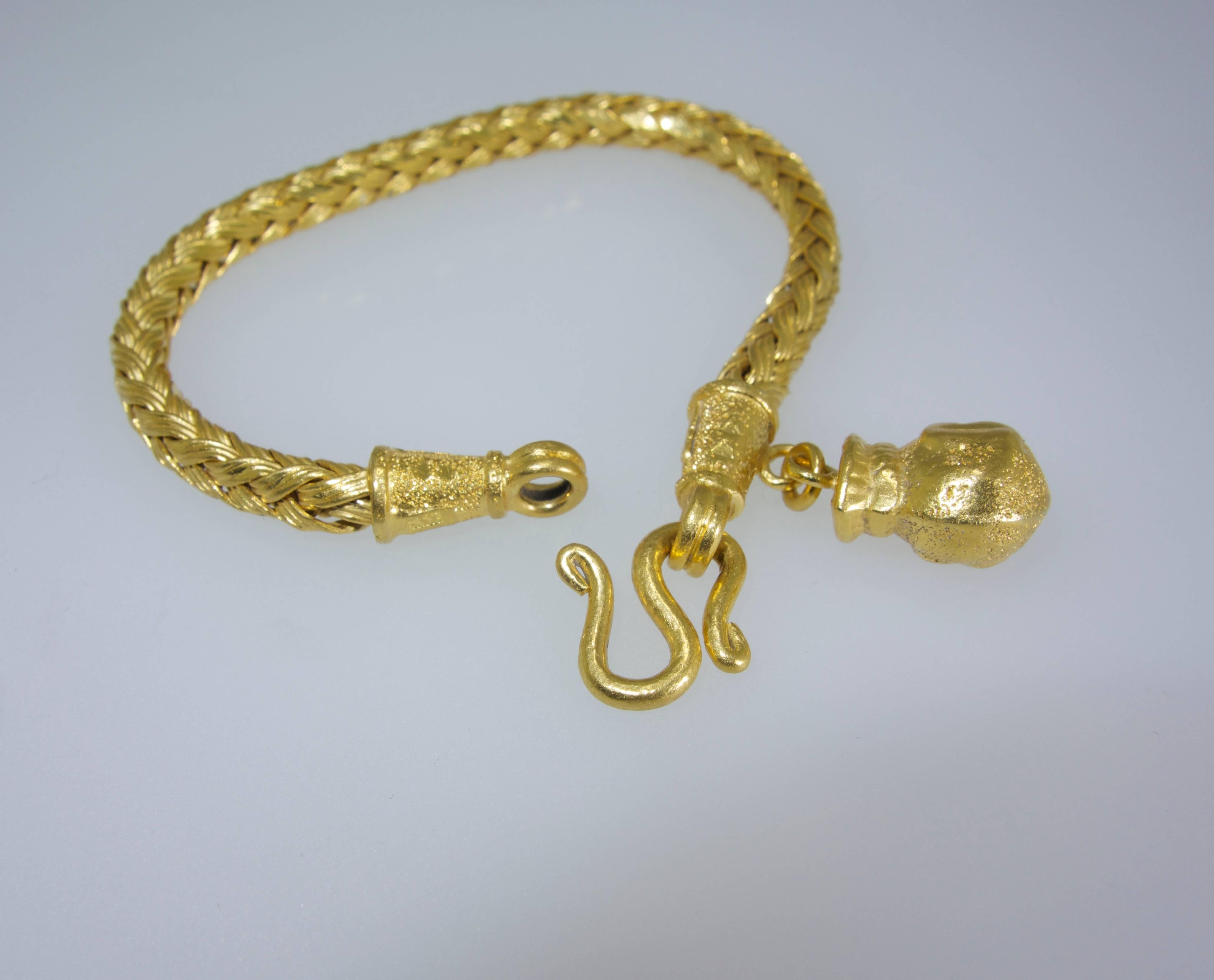 Probably over 22K yellow gold and weighing 30.3 grams, this braided bracelet with a "gold pot" motif charm is well made, flexible and versatile.  It is 6.5 inches long. 