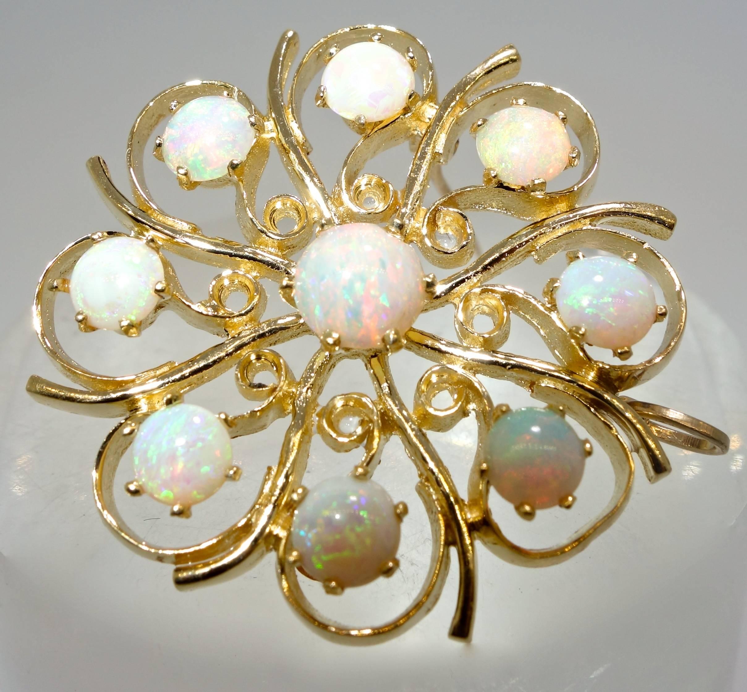 In a swirl like motif, nine opals are set into gold creating a colorful statement.  This piece, which is 1.5 inches in diameter weighs 10 grams, and can be worn both as a brooch and as a pendant.