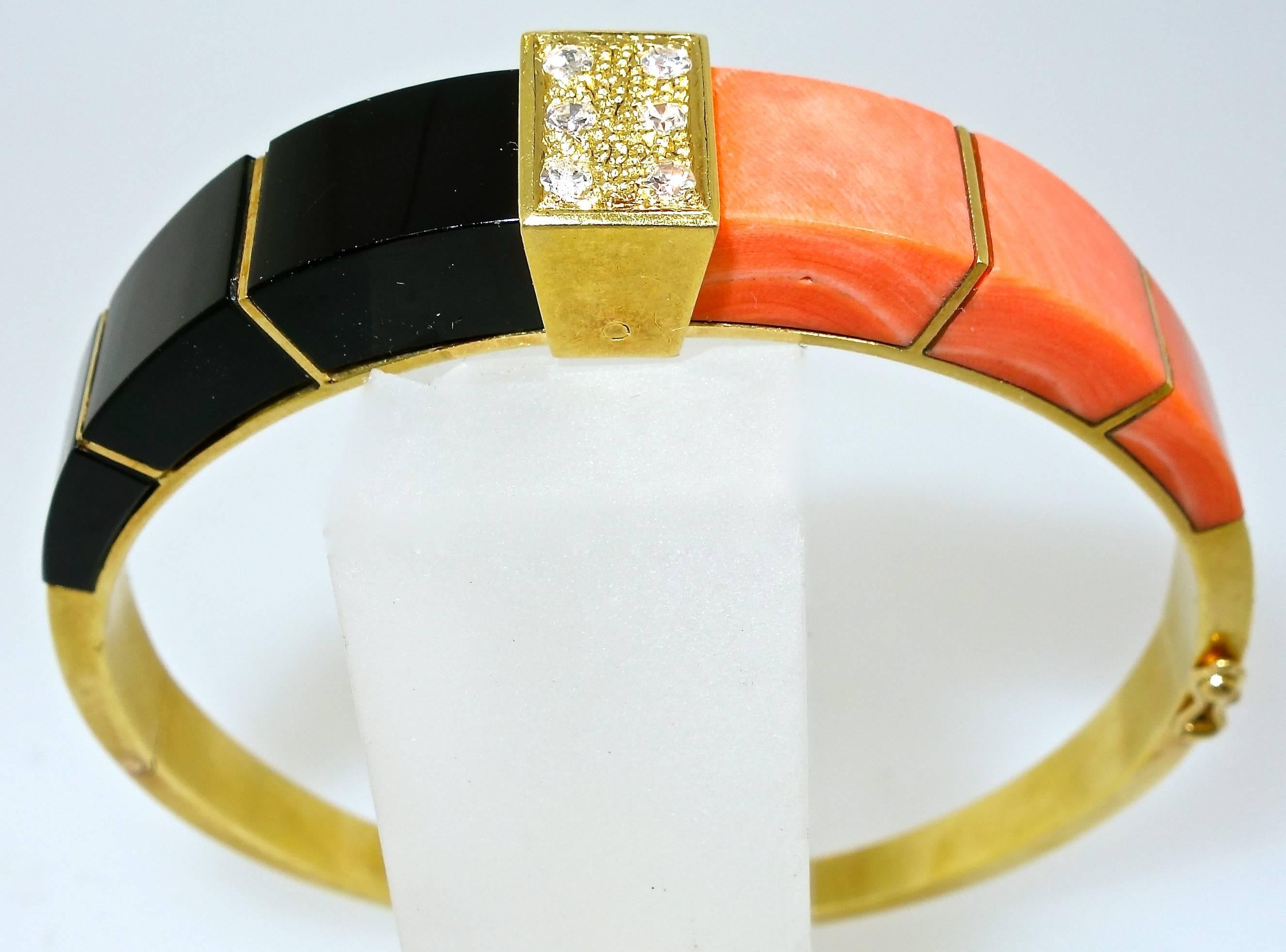 Onyx and coral create a striking color contrast in this bold and substantial 18K bangle bracelet which centers six round brilliant cut fine white diamonds, weighing approximately .20 cts.  This bracelet has a seven inch interior dimension, and