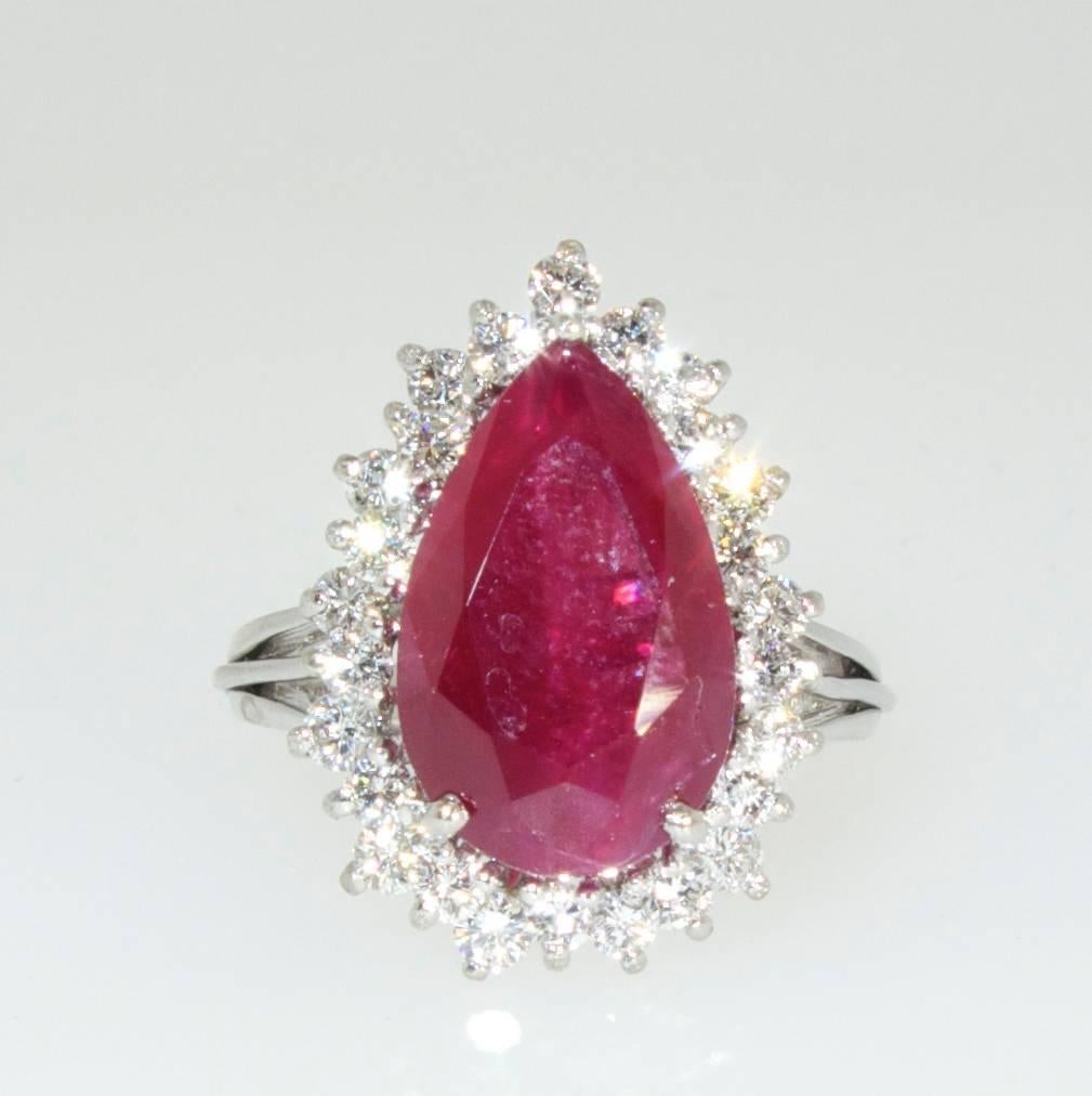 Fine pear cut natural ruby weighing 6.8 cts, displaying a fine vivid red color, slightly included and surrounded by white brilliant cut diamonds, H, and very slightly included, weighing .90 cts. 18K white gold hand made fine mounting which is easily