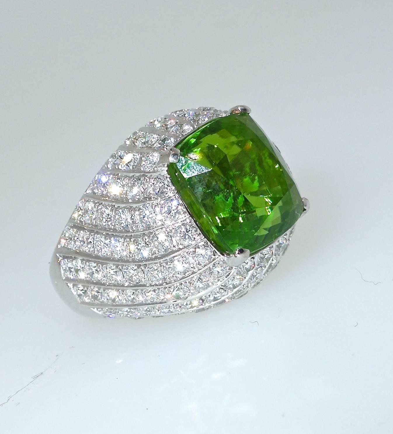 The center fine natural peridot displays a bright green color with no undertones of brown.  The stone weighs 11.7 cts and is clean and well cut.  In a swirl design leading up to the peridot are approximately 3.63 cts of fine white diamonds all near