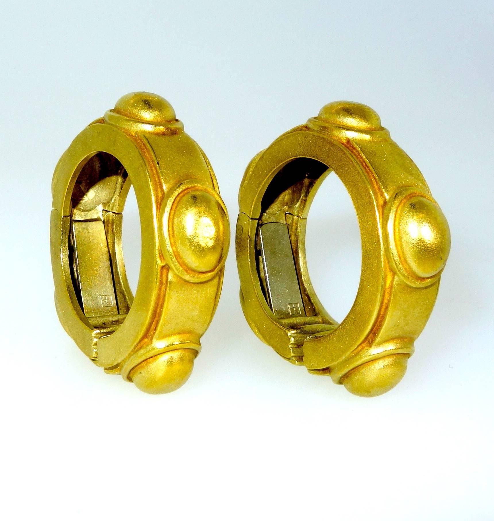 18K green gold stylized hoops.  Substantial in feel and well balanced for comfort on the ear, these unusual earrings, models we have not encountered previously, are now clip on and can be altered for a pierced ear.  1.25 inches in diameter, and 3/8