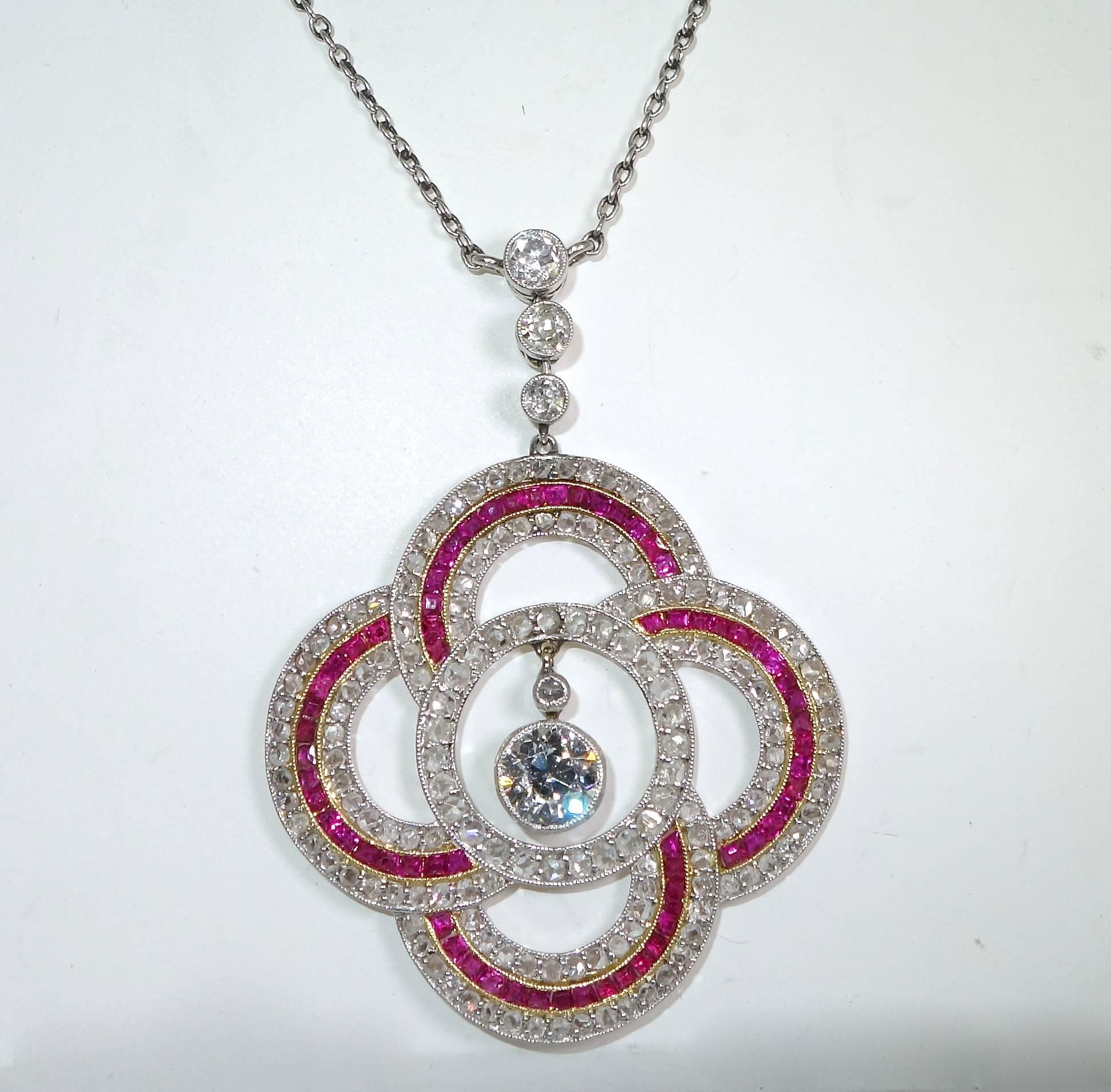 Calibre cut natural fine rubies and rose and European cut diamonds set in a quatrefoil design with a hanging European cut diamond in the center.  This pendant is finely made and is suspended from a 16 inch platinum chain.  There are over 150