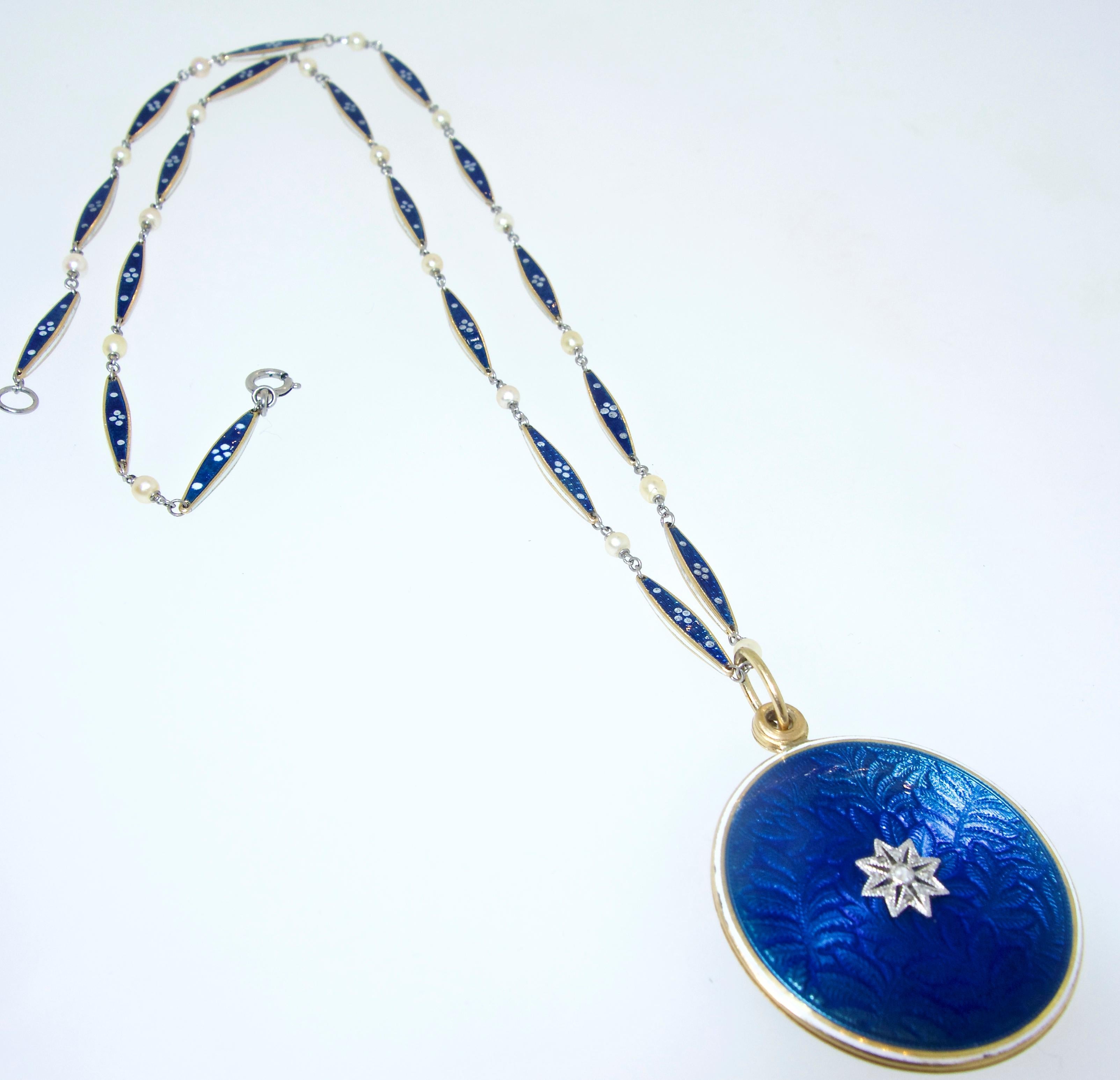 Antique locket both sides of which has guilloche blue enamel, white opaque enamel, natural pearls, and on the front a rose cut diamond floret in platinum The locket slides to the side when one wants to see the enclosed photos, then remains shut as a