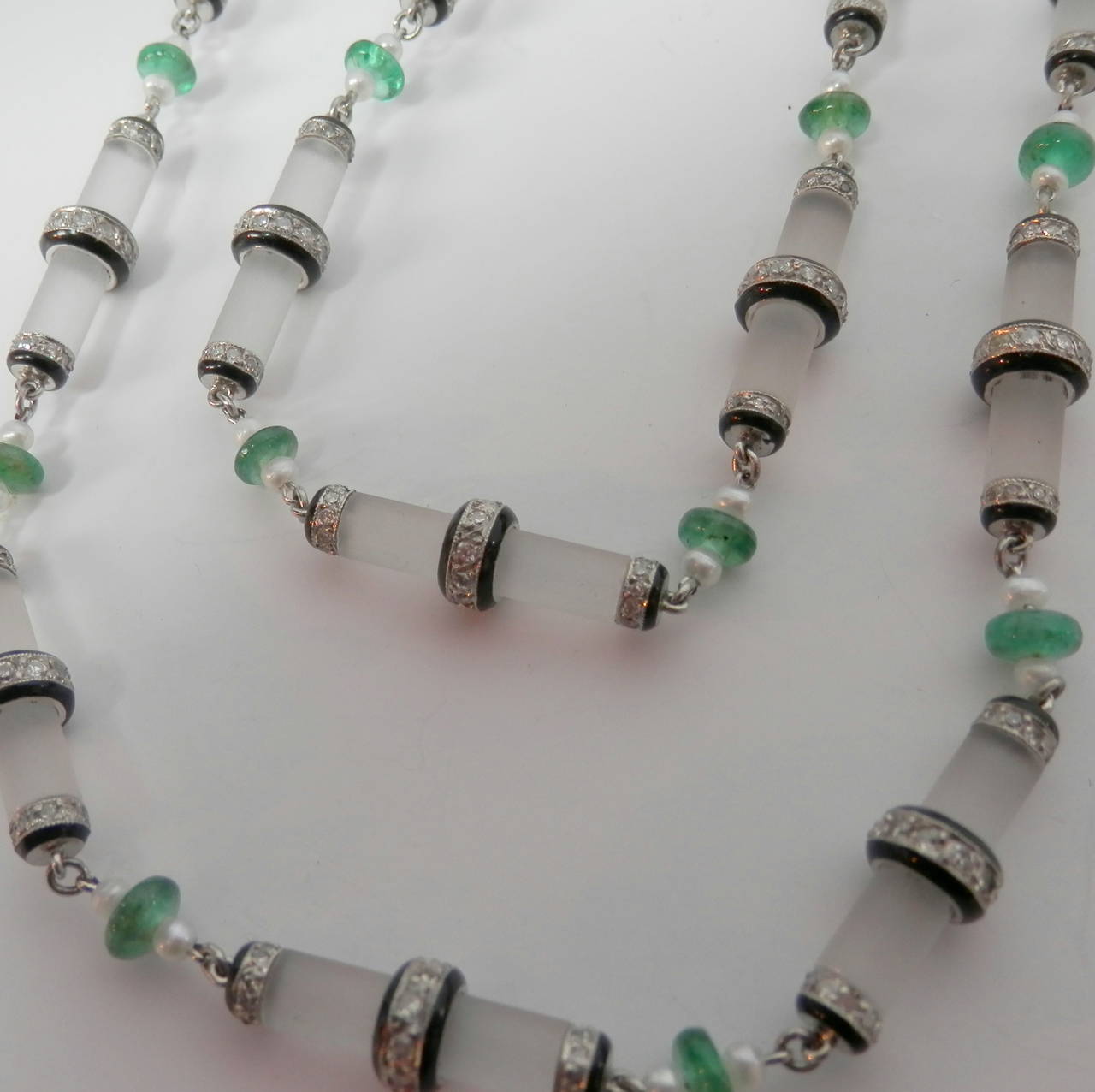20 Frosted rock crystal accented with small diamond roundels further accented with black enamel.  Interspersed are 20 small emerald beads with small white pearls on either side. 26 inches long.