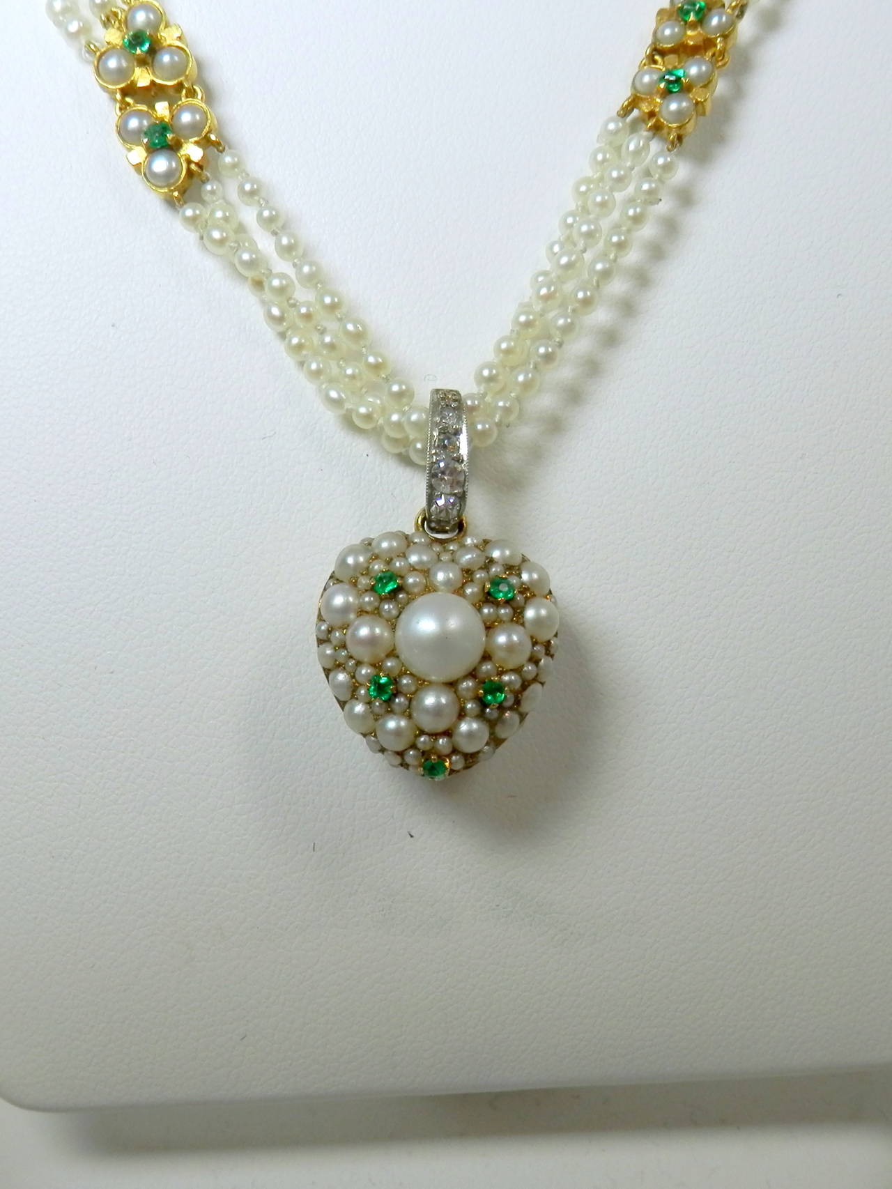 18K Natural pearls, emeralds and small diamonds decorating the gold and platinum bale.  The heart is signed on the inside Tiffany & Co.  The small emerald and pearl motifs along the chain are decorated on both side.  26 1/2 inches long. Victorian,