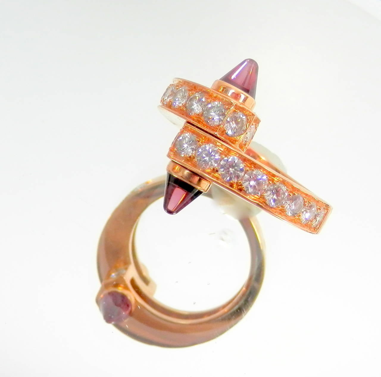 18K pink gold,  garnet and 20 diamonds with an average diamond color of E and VVS2  All the diamonds have an estimated weight of 1.68 cts.  The ring is signed Cartier, 750, numbered and with hallmarks.  Inside the shank is also the European ring